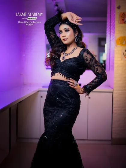 A full-length pose of a glamorous look in a black embroidered outfit. The dramatic pose and confident expression are part of the overall presentation we teach.