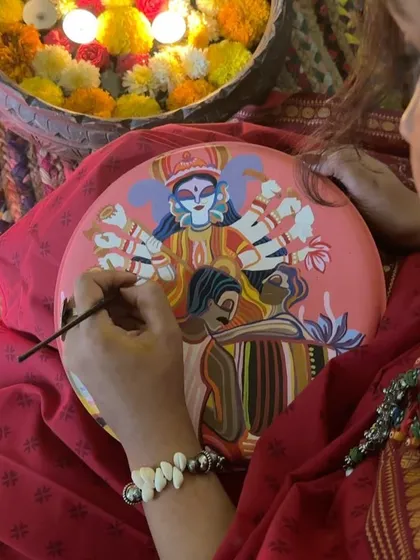 A team member painting the main Durga plate, a design full of divine energy and color.