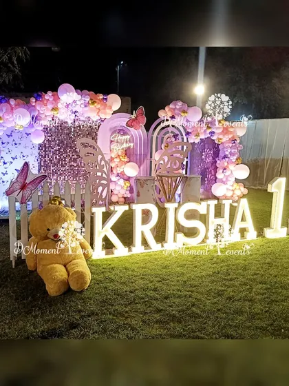 A slightly different angle of Krisha's butterfly-themed party, highlighting the crowned teddy bear and the intricate details of the balloon and butterfly decorations.