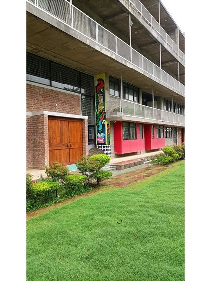Another view of the Eklavya campus entrance, highlighting the integration of landscaping and colorful architectural elements. The building is designed to be a welcoming and stimulating environment.