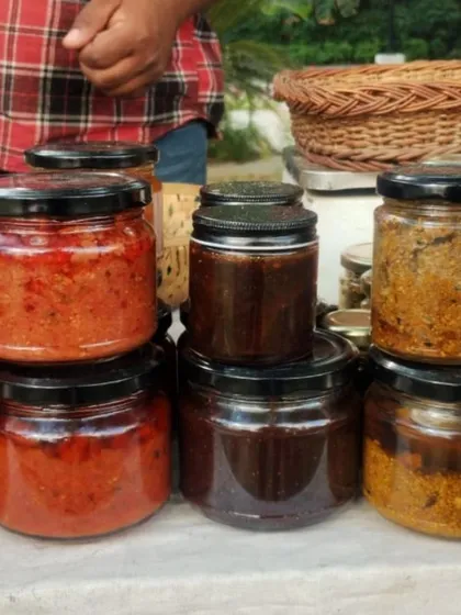 A stack of glass jars filled with colourful homemade pickles and chutneys.