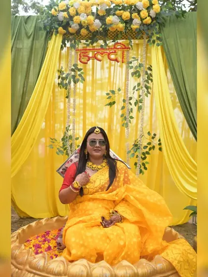 Our Haldi ceremony decor includes traditional elements like this large, ornate urli bowl for the bride. The backdrop is a cascade of yellow marigolds and bright fabric drapes, creating a picture-perfect traditional setting.
