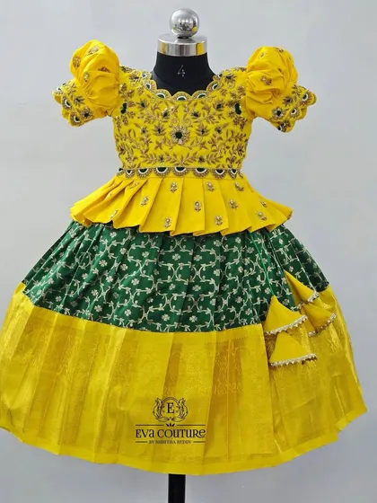 A unique combination of yellow and green. This Pattu Pavadai features a patterned green skirt and a yellow peplum blouse with intricate embroidery.
