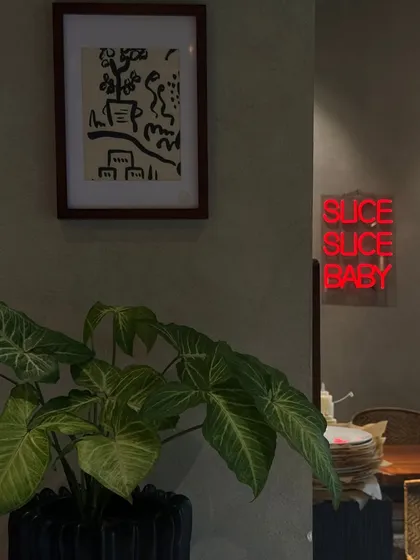 The interior of my restaurant combines modern art, lush greenery, and a playful neon sign. I wanted to create a vibe that is both stylish and comfortable, inviting you to stay a while.
