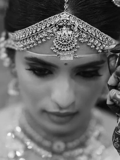 A stunning black and white portrait of the bride, her henna-adorned hand delicately touching her headpiece. This artistic shot is full of grace and emotion.