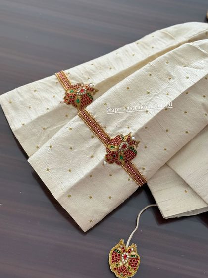 An off-white blouse with armlet-style embroidery on the sleeves.