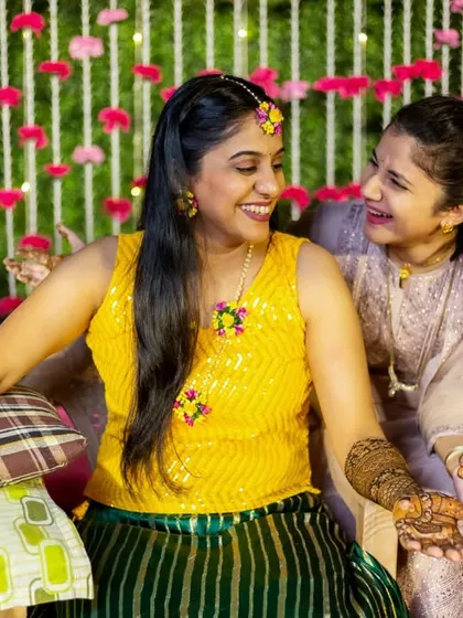 Candid moments during the mehendi application. The bride shares a laugh with her friends while getting her henna done.
