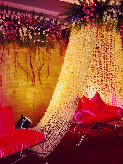 A unique reception seating area I designed with a curtain made of hanging jasmine strings. The top border is a mix of colorful exotic flowers and hanging roots for a dramatic effect.