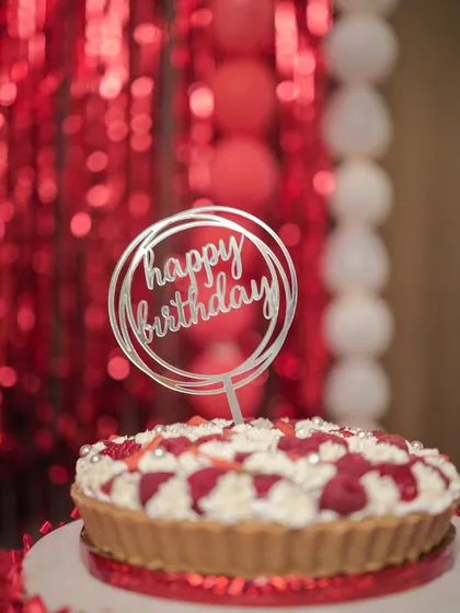 My raspberry and strawberry cheesecake tart, ready for a party with a 'Happy Birthday' topper and a festive red background.