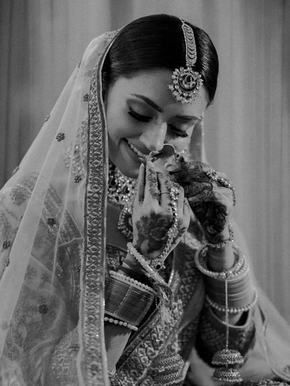 A timeless black and white portrait of a bride, her smile gentle and her eyes full of emotion. This photo focuses on her expression and the beautiful details of her jewelry.