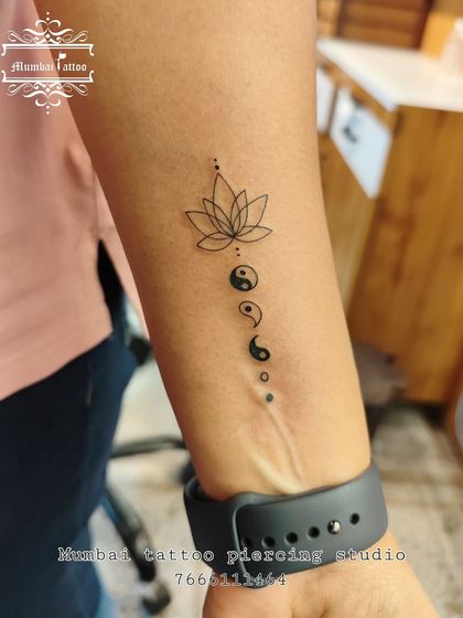 A spiritual tattoo combining a lotus flower with a cascade of yin-yang symbols. This design represents the journey to enlightenment and finding balance along the way.