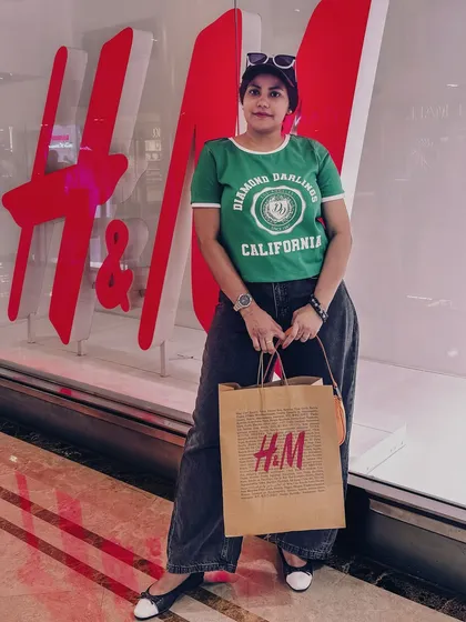 Standing in front of an H&M store logo, proudly displaying my shopping haul.