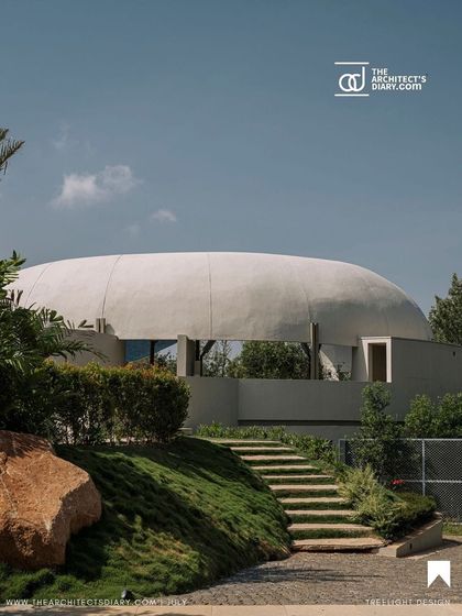 The spa building's unique dome-like structure, crafted from ferrocement, rises from the landscape. The design is partially nestled into the earth, with stone steps leading up, minimizing its visual impact and integrating it with the site's natural slope.