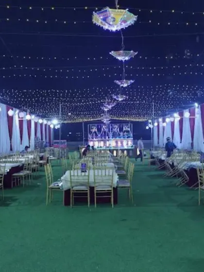 The outdoor dining arrangement at Sky Banquet hall in Kharghar. The lawn is covered with a tent and decorated with string lights, providing a comfortable and festive space for guests.