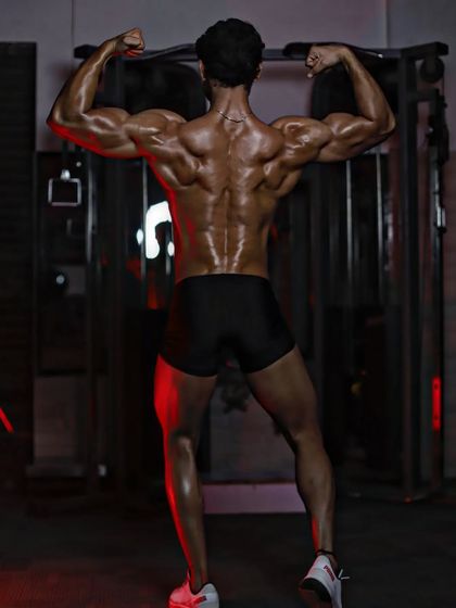A full back double biceps pose under dramatic lighting. This highlights every muscle from my traps down to my calves.