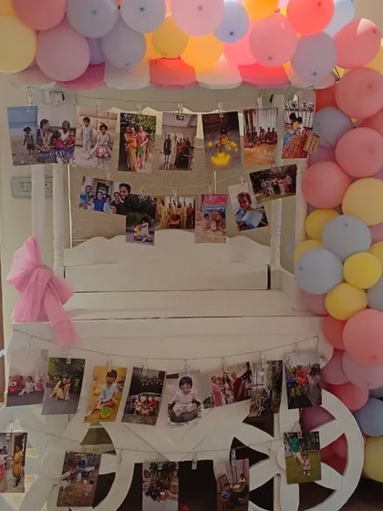 A charming memory cart decorated with photos and a pastel rainbow balloon arch. This is a wonderful and personal way to display cherished moments at a birthday party or anniversary.