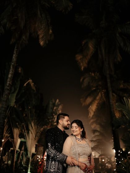 A tender moment captured against the dramatic silhouette of palm trees at night. This image has a timeless, romantic quality, focusing on the couple's embrace.