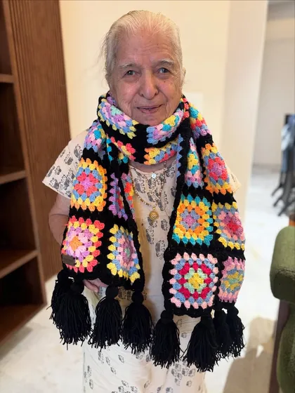 Dadi is all smiles showing off this vibrant granny square muffler. Made with soft 4-ply yarn and finished with playful tassels, it’s designed to keep you warm while adding a pop of cheerful color to your winter wardrobe.