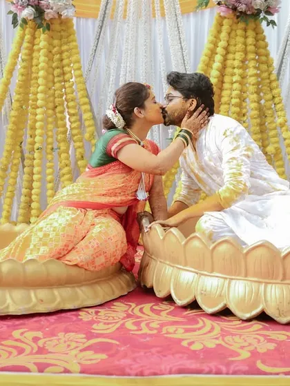 A celebratory kiss during the Haldi ceremony. The beautiful lotus-shaped seating and vibrant decor make for a stunning backdrop.