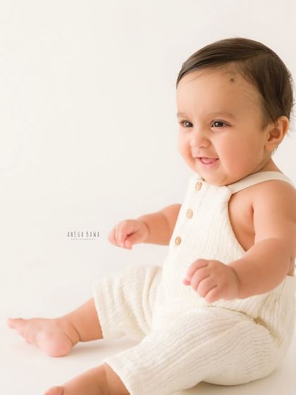 A simple and sweet portrait of a sitting baby. The clean white background puts all the focus on his happy expression and adorable pose.
