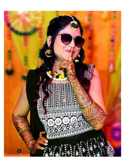 A stylish bride posing with sunglasses during her Mehndi function, adding a modern twist to a traditional event.