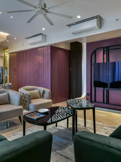 This living room design prioritizes a bold, artistic atmosphere. The rich grape color is the star, balanced by beige wallpaper and furniture that is like art itself, including a console combining wood and a Mimosa hued finish.
