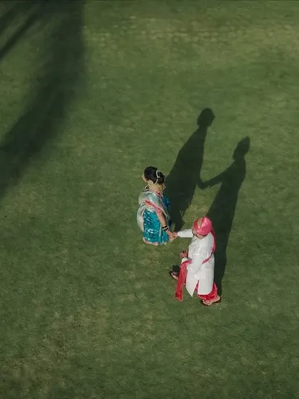 A unique perspective from above. This drone shot captures the couple in their wedding attire, creating long, dramatic shadows on the green lawn. It's a modern and artistic way to capture a wedding portrait.