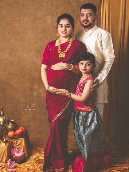 A complete family portrait from a traditional maternity session. The expecting mother, father, and their daughter are all dressed in beautiful ethnic attire, creating a perfect family memory.