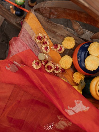 The texture and color of the mother's dupatta, featuring Gowri motifs, are highlighted in this shot. We added Gota Patti flowers and marigolds to complement the fabric's beauty.