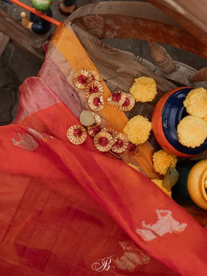 The texture and color of the mother's dupatta, featuring Gowri motifs, are highlighted in this shot. We added Gota Patti flowers and marigolds to complement the fabric's beauty.