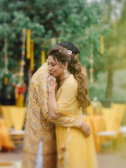 A tender hug shared between the couple during their Haldi ceremony. The soft focus and warm lighting create a deeply romantic and emotional photograph.