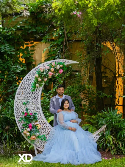 A beautiful couple's portrait on the floral crescent moon prop, set against a lush garden backdrop.