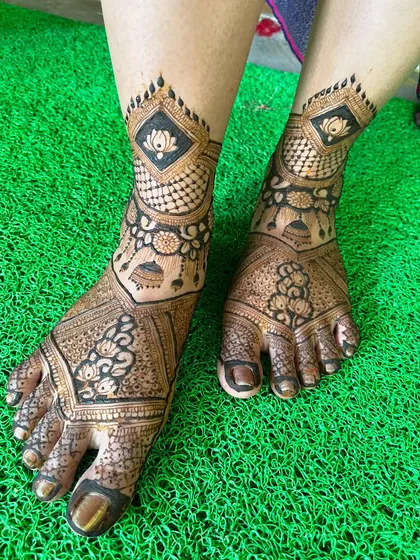 The lotus and jhumka leg design, photographed on a bright green background. The contrast makes the henna design stand out beautifully.