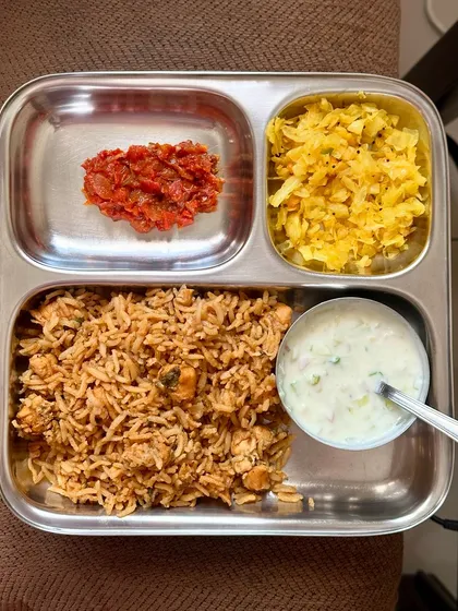 A simple meal of chicken rice, cabbage palya, tomato chutney, and raita. This is a quick and easy lunch that is both delicious and healthy.