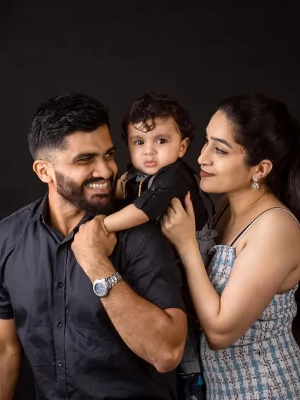 A beautiful candid-style family portrait against a dark background.