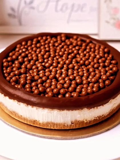 A delightful cheesecake with a crunchy base, topped with a thick layer of chocolate and crispy chocolate balls.