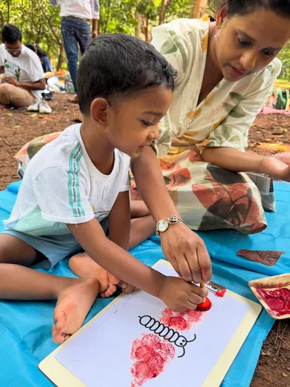 This young boy is carefully stamping red patterns to create a caterpillar. This activity combines art with learning about insects, making the experience both fun and educational.