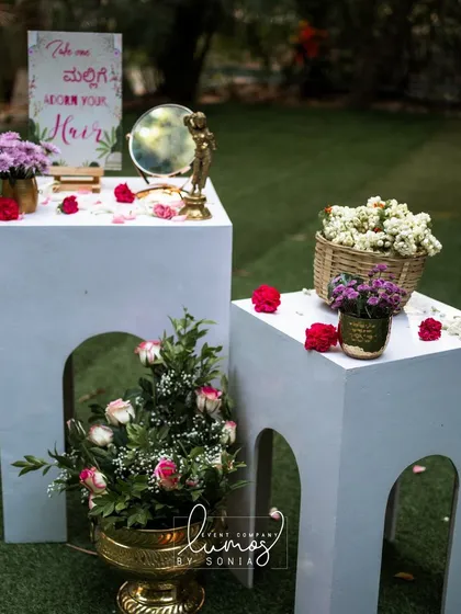 Another angle of the "Adorn Your Hair" station, set up on elegant white pedestals in a garden.