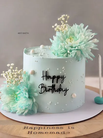 A pastel blue cake with fresh flowers, showcasing an elegant and simplistic design. This is a Strawberry and Chocolate cake.