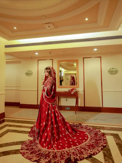 A stunning full-length photo of the bride in a hotel corridor. Her red gown with its long train makes a powerful statement.
