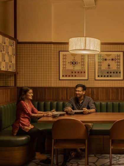 At the Grid Pavilion outlet of Eat Punjab, we designed a variety of seating arrangements to suit different moods. This intimate corner features a continuous forest green sofa, mustard yellow tiles, and custom artworks inspired by Punjab's Phulkari textile craft, creating a cozy and culturally rich dining spot.