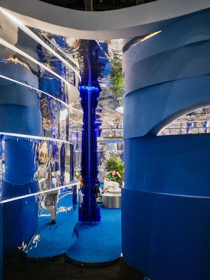 From this angle, you can see how the layered blue waves on the wall interact with the reflective chrome surfaces. This interplay of solid color and distorted reflection was key to creating a space that felt both grounded and otherworldly.