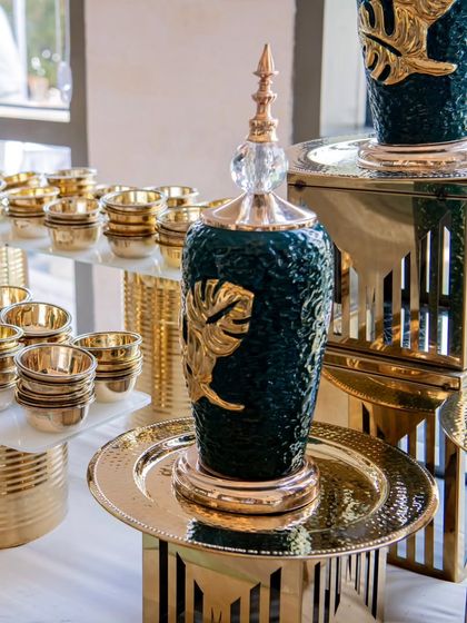 A close-up of the exquisite details in my buffet decor. This decorative green and gold urn, paired with hammered gold platters, showcases the premium quality of my serveware that elevates any event's ambiance.