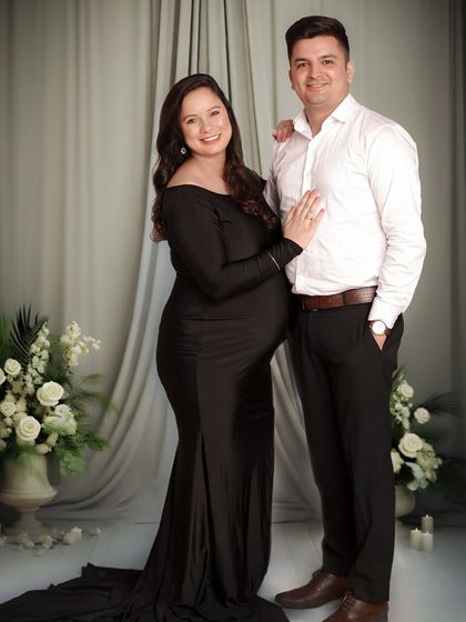 A formal and graceful couple's portrait. The mom-to-be wears a floor-length black gown, creating a timeless and sophisticated image.