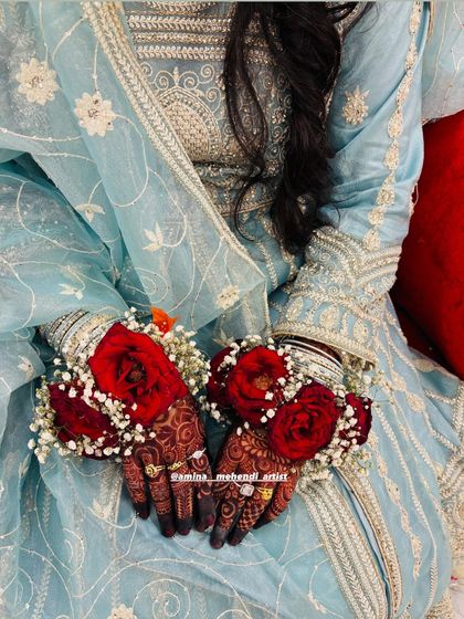 A beautiful shot of the bride in her light blue outfit, with the red floral bracelets and dark henna providing a stunning contrast.