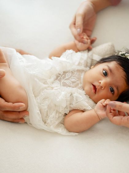 A parent's hands gently holding their baby's legs and hands. This shows the scale of how tiny she is in these first few weeks.