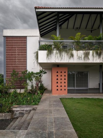 The exterior of this home combines a traditional sloping roof and open terrace with modern elements like a brick screen and clean white walls.