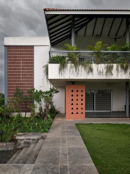 The exterior of this home combines a traditional sloping roof and open terrace with modern elements like a brick screen and clean white walls.
