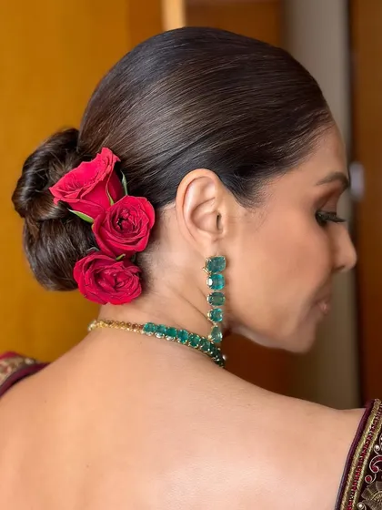 A view of the elegant floral bun that completed this festive look. The sleek hair provides the perfect contrast to the bold, smoky eyes and rich velvet blouse.