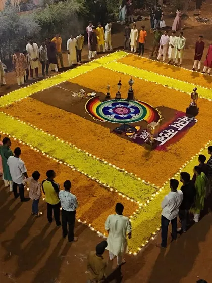 Players and members standing around the beautiful rangoli made for the occasion.